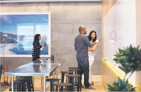  ?? Lea Suzuki / The Chronicle ?? Ephraim Tekle (center), senior engineerin­g manager, and Jasleen Kaur, program manager, at the white board in WeWork’s space.