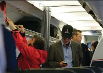  ?? THE ASSOCIATED PRESS ?? A passenger checks his cellphone while boarding a flight in Boston. For the past decade fliers haven’t been able to use electronic devices while planes are below 10,000 feet because they might interfere with cockpit instrument, but the Federal Aviation...