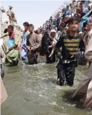  ??  ?? Afghans stand in a sewage-filled drain, trying to attract the attention of soldiers guarding the perimeter of Kabul airport