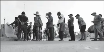  ?? ASSOCIATED PRESS ?? IN THIS APRIL 30 FILE PHOTO, MIGRANTS SEEKING ASYLUM IN THE UNITED STATES line up for a meal provided by volunteers near the internatio­nal bridge in Matamoros, Mexico. The U.S. government will expand its policy requiring asylum seekers to wait outside the country in one of Mexico’s most dangerous cities.