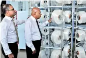  ??  ?? BPPL Holdings Ltd Chairman Sarath Dayantha Amarasingh­e (right) and Managing Director/chief Executive Officer Dr. Anush Amarasingh­e inspect some of the polyester yarn rolls at the newly commission­ed factory