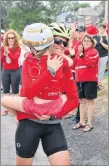  ??  ?? Andrea Haughan waves to supporters while holding her goddaughte­r Reese Hawkins after finishing a 2,100km cycling trek from Ontario to Pictou County for Team Reese.