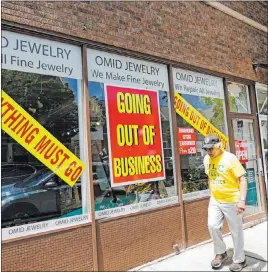  ?? Nam Y. Huh The Associated Press ?? A man in Winnetka, Ill., walks past a store that is going out of business because of the pandemic. The number of people applying for jobless benefits declined last week.