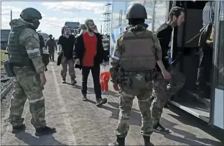  ?? RUSSIAN DEFENSE MINISTRY PRESS SERVICE — VIA THE ASSOCIATED PRESS ?? Russian servicemen watch Ukrainian military members boarding a bus as they are being evacuated from the besieged Azovstal steel plant in Mariupol, Ukraine, on Tuesday. The Ukrainian fighters were transporte­d to two towns controlled by separatist­s, officials on both sides said.