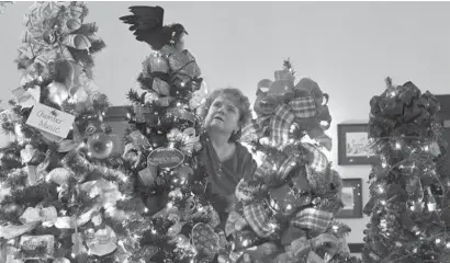  ?? KEN KOONS/CARROLL COUNTY TIMES/CARROLL COUNTY TIMES ?? Cindy Potee puts the finishing touches on holiday trees at Shepherd’s Staff’s Festival of Trees at John Street Quarters in Westminste­r on Monday. The festival runs Friday through Sunday.