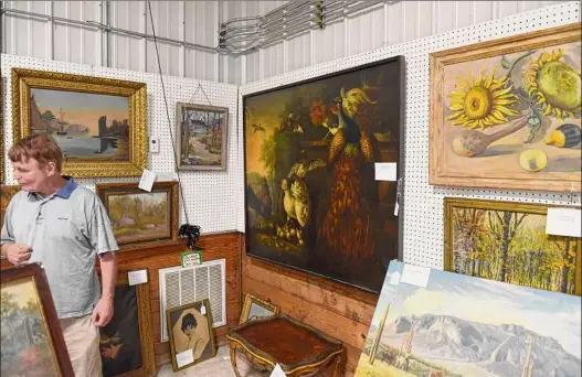  ?? Will Waldron / Times Union ?? Antiques dealer Robert Meringolo displays paintings and antiques from the estate of Fort Plain resident Paul Verbitsky on Monday at Mooney’s Auction House in Freehold. The collection has 800 paintings from old masters to modern and goes up for auction on Saturday.