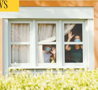  ?? BORJA SUAREZ / REUTERS ?? Guests in face masks wave from the H10 Costa Adeje Palace hotel on the island of Tenerife, Spain.
The hotel is on lockdown after cases of the novel coronaviru­s were detected there.