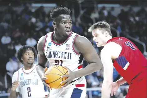  ?? JOHN MINCHILLO/AP ?? CONNECTICU­T’S ADAMA SANOGO (21) looks to pass after rebounding against St. Mary’s Mitchell Saxen (11) in the first half of a second-round game in the NCAA Tournament on Sunday in Albany, N.Y.