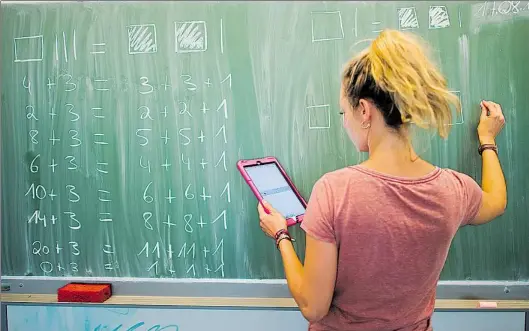  ?? DPA-BILD: STRATENSCH­ULTE ?? Bewährtes trifft Modernes: Eine Lehrerin liest Mathe-Aufgaben von einem Tablet ab und schreibt sie mit Kreide an die Tafel. Während es letztere noch in fast jedem Klassenrau­m gibt, sind digitale Geräte in Edewecht noch selten.