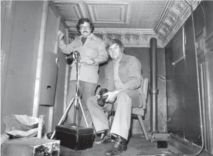  ?? SUN-TIMES FILE ?? Using an automatic shutter release on another camera, Sun-Times photograph­ers Gene Pesek (right) and Jim Frost photograph­ed themselves in the hideaway they worked undercover from at the Mirage tavern.
