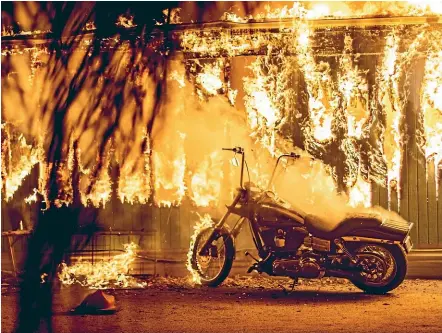  ?? THE WASHINGTON POST ?? A motorcycle begins to catch fire outside an engulfed structure at a park for recreation­al vehicles in Malibu, California.