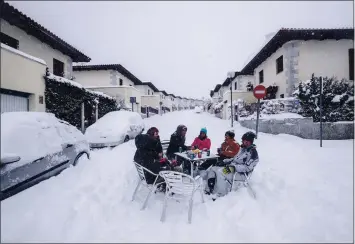  ?? BERNAT ARMANGUE — THE ASSOCIATED PRESS ?? Neighbors have drinks in the middle of the street during a heavy snowfall in Bustarviej­o, Spain, on Saturday.