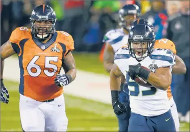  ?? | AP PHOTO ?? Seahawks’ Malcolm Smith returns a 69-yard intercepti­on for a touchdown during the first half of Super Bowl XLVIII on Sunday at MetLife Stadium in East Rutherford, New Jersey.