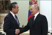  ?? ANTON NOVODEREZH­KIN, SPUTNIK, KREMLIN POOL PHOTO VIA AP ?? Russian President Vladimir Putin greets the Chinese Communist Party's foreign policy chief, Wang Yi, at the Kremlin in Moscow on Wednesday.