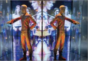  ?? ?? A reflection of the costume that David Bowie wore as Ziggy Stardust on tour and during a performanc­e of “Starman” on British pop music show “Top of The Pops” is shown as part of a retrospect­ive David Bowie exhibition, entitled “David Bowie Is” at the V&A Museum in west London in 2013.