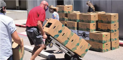  ?? Photo by Gary Herron, Rio Rancho Observer ?? Bill Stivers, the Sandoval County site supervisor for Meadowlark Senior Center in Rio Rancho, wheels a few more boxes of produce from a truck to be delivered to MSC members in June during the pandemic. The produce came from the New Mexico Grown Fruits and Vegetable for Senior Meals Pilot Program.