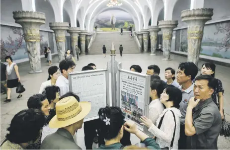  ?? Picture: AFP ?? Train commuters gather to read the latest copy of Rodong Sinmun showing images of North Korean leader Kim Jong-un meeting US President Donald Trump during their historic summit in Singapore yesterday. Trump also accepted an invitation from Kim to visit...