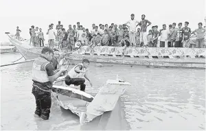  ??  ?? TRAGIK: Anggota polis memeriksa cebisan bot yang terbabit dalam pertembung­an dengan kapal membawa muatan pasir di Madaripur, semalam.