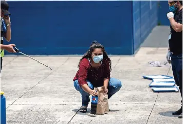  ??  ?? Vanessa Díaz recoge la comida que su madre le lleva al sitio donde los migrantes que regresan deben pasar dos semanas en cuarentena