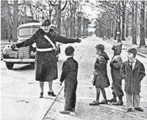  ?? TRIBUNE ARCHIVE ?? Mrs. Peter J. Alt, the first Evanston woman to be hired as a school crossing guard, helps children across an Evanston street corner in 1942.