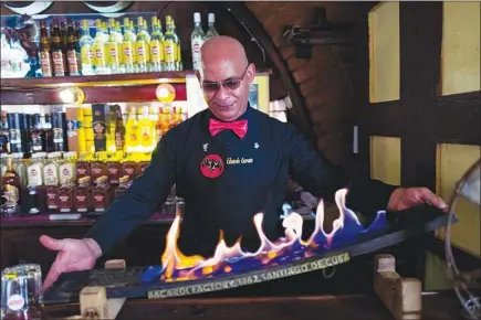  ?? PHOTOS BY ELIANA APONTE TOBAR / THE NEW YORK TIMES ?? Eduardo Corona prepares a special mojito drink at El Traguito, a bar in Santiago de Cuba. Rum became a refined drink in this city far from the tourist-heavy Havana, and its best bar may be the one located in the basement of a sparse museum.