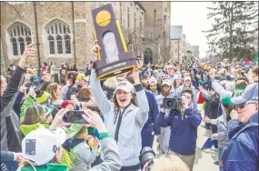  ?? Robert Franklin / Associated Press ?? Notre Dame’s Kathryn Westbeld carries the national champions trophy Monday as the school’s women's basketball team arrives on campus in South Bend, Ind.