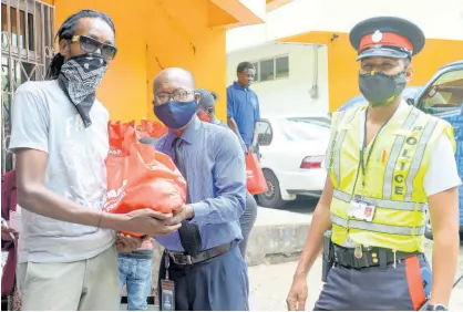  ?? CONTRIBUTE­D ?? NCB’s Gratitude Bus was on the move with the support from the members of the Jamaica Constabula­ry Force. NCB’s Devon Wilson (centre) hands over a care package to resident of the Mount James community in Stony Hill, St Andrew. These care packages were provided in partnershi­p via the Private Sector Organisati­on of Jamaica COVID-19 Jamaica Response Fund. The NCB Foundation has committed a total of J$10 million to assist with food security for the most vulnerable.