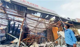  ?? Photos by M. Sajjad ?? ALL GUTTED: A shopkeeper checks the losses at Ajman’s Popular Souq, known as Irani Market, on Thursday after a fire gutted 125 shops on Wednesday. —