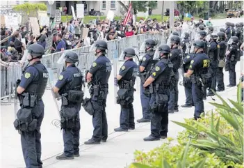  ?? JOE BURBANK/ORLANDO SENTINEL ?? Protesters shout at officers lined up in front of the Orlando Police Department in Orlando on June 3. In the city of Orlando, 37% of residents are white, but about 60% of Orlando Police Department officers are, according to Census and state data. Black residents account for 24% of the city’s populace but 14% of its police.