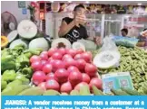  ?? — AFP ?? JIANGSU: A vendor receives money from a customer at a vegetable stall in Nantong in China’s eastern Jiangsu province.