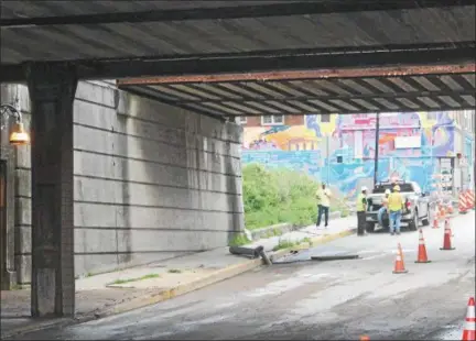  ?? OSCAR GAMBLE — DIGITAL FIRST MEDIA ?? A work crew convenes after clearing a formerly flooded stretch of road under the DeKalb Street Bridge in Norristown on Monday. The bridge was temporaril­y closed due to morning drivetime flooding.