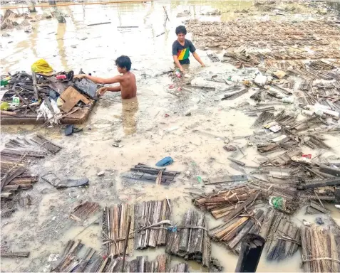  ?? BANAYNAL
ALDO NELBERT ?? Broom makers in Barangay Paknaan, Mandaue City try to salvage some of their raw materials from the flood.