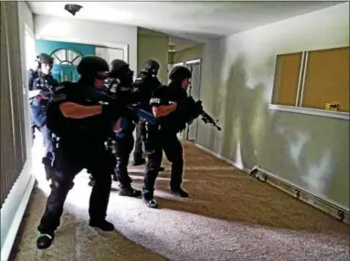  ?? DAN SOKIL - DIGITAL FIRST MEDIA ?? Montgomery County SWAT Team - Central Region members raise their weapons as they storm into the living room of a vacant house in the 2000 block of Orvilla Road, just north of Cowpath Road, in Hatfield Township on Wednesday.