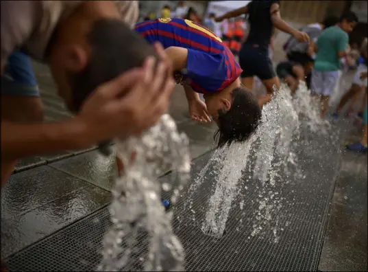  ?? Alvaro Barrientos The Associated Press ?? People cool off in a fountain Saturday in the Basque city of Vitoria, northern Spain.