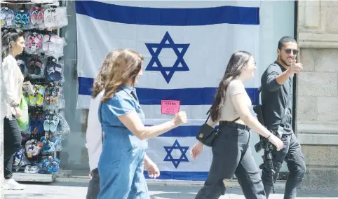  ?? (Marc Israel Sellem/The Jerusalem Post) ?? PEOPLE IN downtown Jerusalem walk past flags on sale for Independen­ce Day this week.