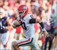  ?? Butch Dill / Associated Press ?? Georgia quarterbac­k Stetson Bennett carries the ball for a first down against Auburn on Saturday. Georgia is the new No. 1 team in the AP Top 25 poll.