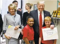  ?? BRANDON/THE ASSOCIATED PRESS ALEX ?? President Donald Trump and Education Secretary Betsy DeVos pose with fourth-graders Janayah Chatelier, 10, left, Landon Fritz, 10, after they received cards from the children Friday during a tour of St. Andrew Catholic School in Orlando, Fla.