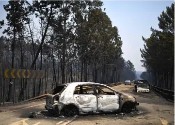  ??  ?? File photo shows burnt cars on a road after a wildfire in Figueiro dos Vinhos. — AFP photo