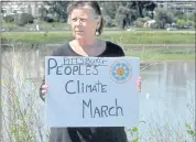  ?? DOUG DURAN — STAFF PHOTOGRAPH­ER ?? Joanne Fanucchi of Pittsburg holds a Peoples’ Climate March sign with the Shell refinery in the background in Martinez on April 21. The refinery has been fined twice.