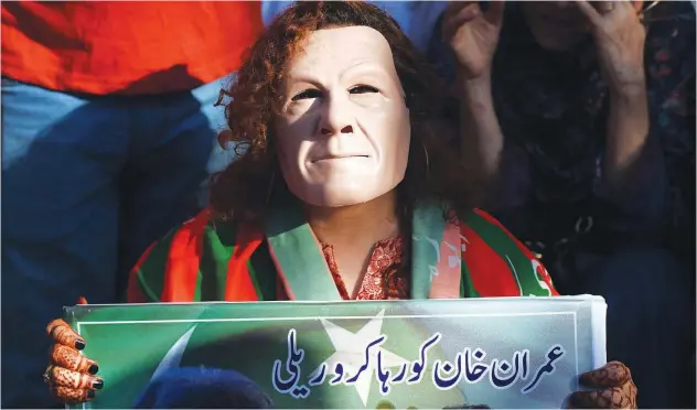  ?? File / Agence France-presse ?? ↑
A PTI supporter wearing a mask resembling Imran Khan, takes part in a rally in Karachi.