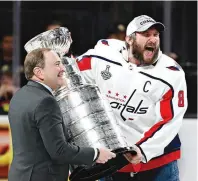  ?? AP Photo ?? Washington Capitals left wing Alex Ovechkin, right, celebrates as he accepts the Stanley Cup from NHL commission­er Gary Bettman after the Capitals defeated the Golden Knights, 4-3, in Game 5 of the Stanley Cup Finals on Thursday in Las Vegas.
