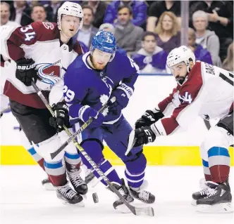  ??  ?? Maple Leafs winger William Nylander battles for the puck with Avalanche centre Carl Soderberg, left, and defenceman Mark Barberio during the second period in Toronto.