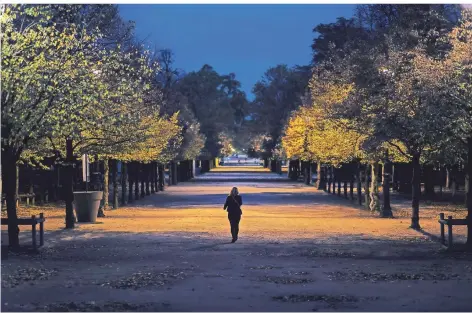  ?? FOTO: LEWIS JOLY/AP ?? Eine Frau geht abends an den leeren Gärten der Tuileries im Pariser Zentrum vorbei.