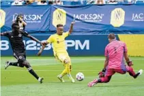  ?? MARK HUMPHREY/AP ?? Nashville SC midfielder Hany Mukhtar, center, tries to get off a shot as he is defended by Inter Miami midfielder Blaise Matuidi, left, and goalkeeper John McCarthy on Sunday in Nashville, Tennessee.