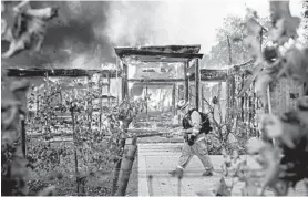  ?? NOAH BERGER/AP ?? Firefighte­r Joe Zurilgen passes a burning home Sunday as the Kincade Fire rages in Healdsburg, Calif. The fire began Wednesday and was only 10% contained, officials said.