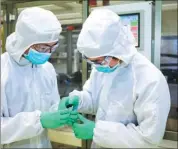  ??  ?? Two researcher­s check battery cells at GM’s battery lab in Shanghai.