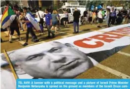  ?? — AFP ?? TEL AVIV: A banner with a political message and a picture of Israeli Prime Minister Benjamin Netanyahu is spread on the ground as members of the Israeli Druze community and their supporters demonstrat­e during a rally to protest against the ‘Jewish Nation-State Law’ in the Israeli coastal city.