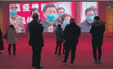  ?? Photograph­s by Ng Han Guan Associated Press ?? PEOPLE at an exhibit on Wuhan’s fight against the virus. Questionin­g the government’s narrative is risky.