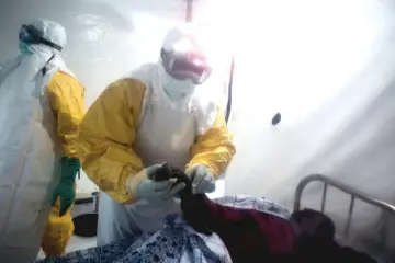  ?? — AFP photo ?? File photo shows an Ebola patient is being checked by two medical workers after being admitted into a Biosecure Emergency care Unite (CUBE) in Beni.