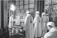  ?? Karine Perret / AFP / Getty Images ?? Worshipper­s wear helmets as they celebrate the first Mass on Saturday in a side chapel behind Notre Dame Cathedral since a fire engulfed the church April 15.